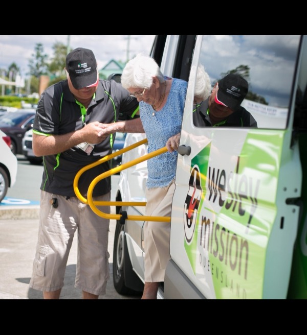 Man assisting woman out of minibus