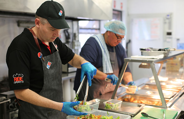 Two chefs in kitchen serving up food