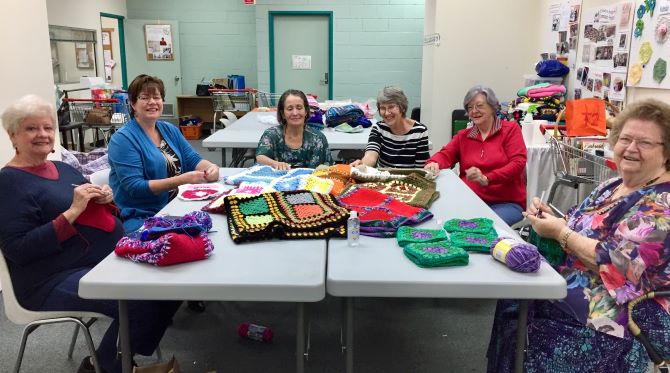 group of women with crochet blankets