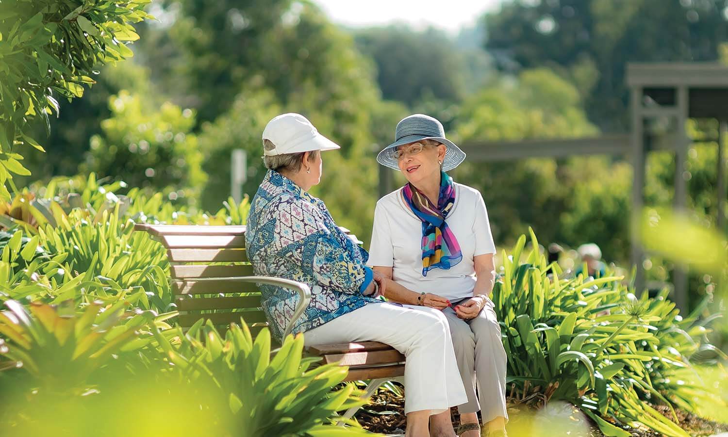 two women sitting on park bench in garden